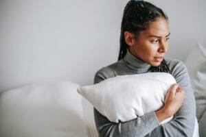 Therapist Tysons Corner VA- woman holding pillowtherapist Tysons Corner VA- upset woman sitting on bed hugging pillow